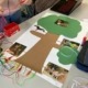 Plakat, auf das ein großer Baum aus buntem Papier sowie Fotos von Tieren aufgeklebt sind. Das Plakat ist über Kabel mit einem Makey Makey verbunden.