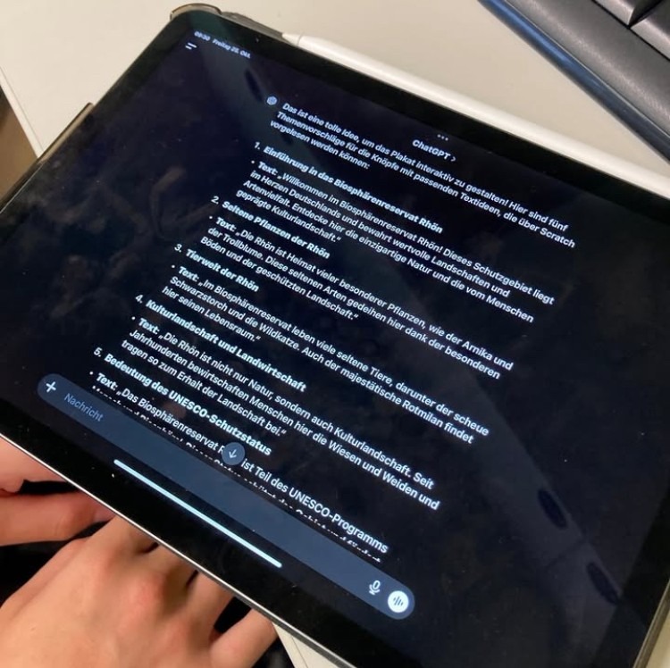 Tablet, auf dem eine Ausgabe von Chat G P T zu sehen ist. Darin stehen Themen-Vorschläge für ein Plakat über das Biosphärenreservat Rhön.